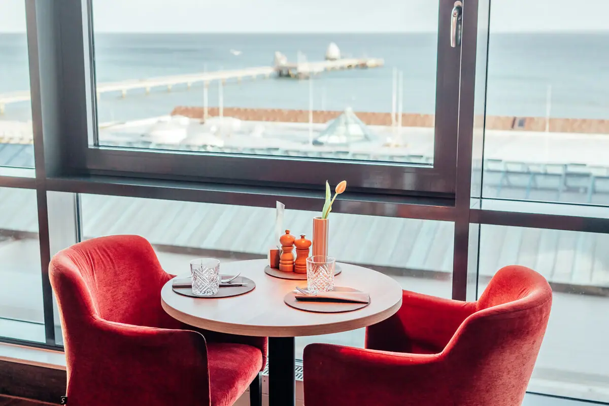 JEDERMANNS Restaurant, Grömitz A table with red chairs and a view of the Baltic Sea