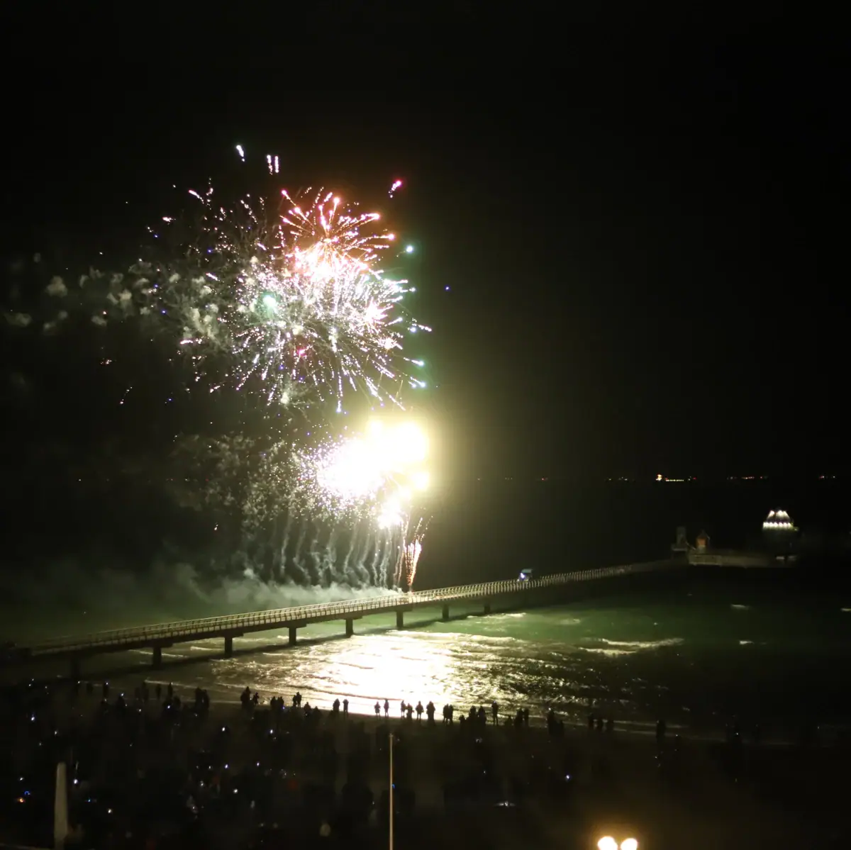 Fireworks over a body of water in the night sky