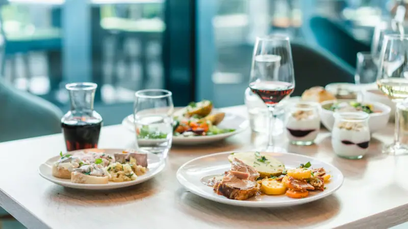 A table with plates full of food and glasses of wine.