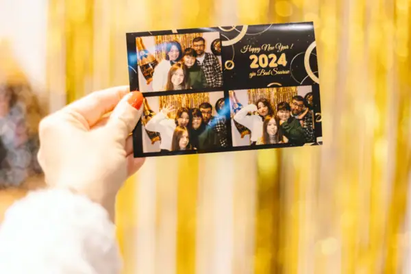 Hand holds a card with a group of people. The card is filled with photos from the evening.