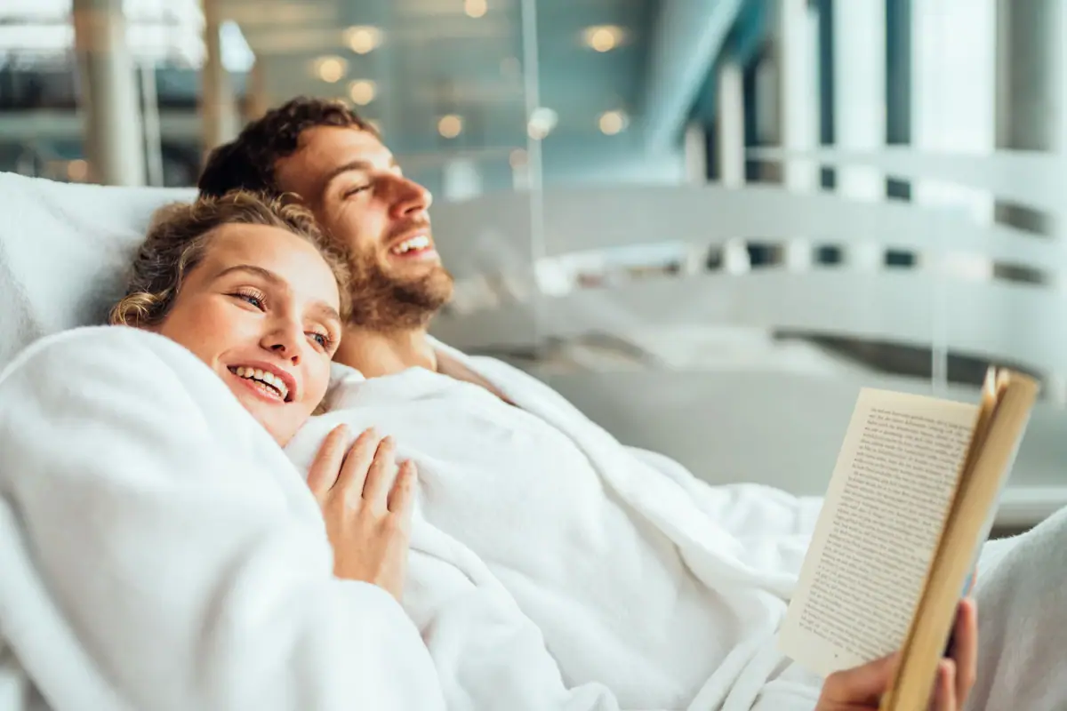 A man and a woman lie smiling in a bed.