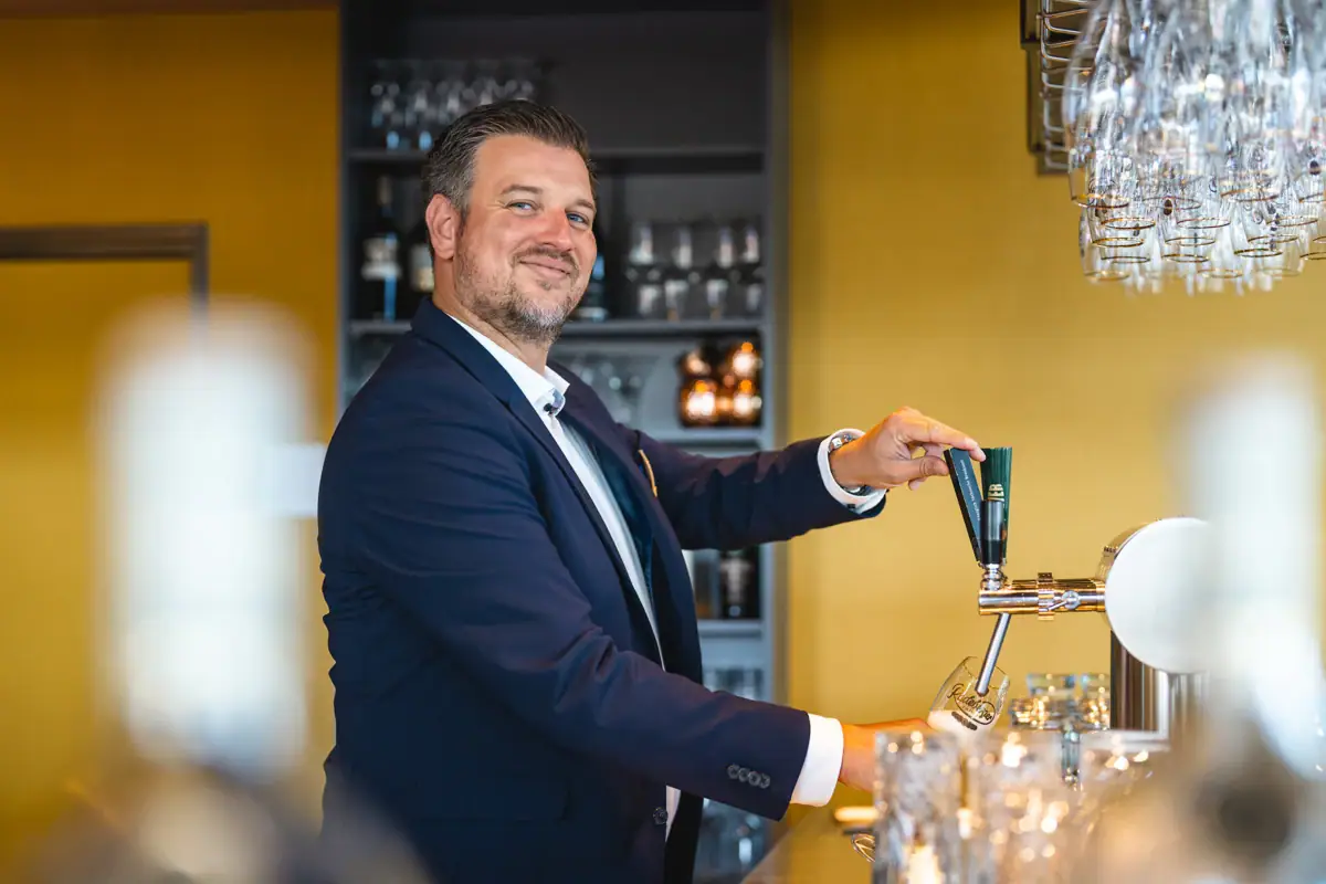 Bartender A man in a suit draws beer from a tap.