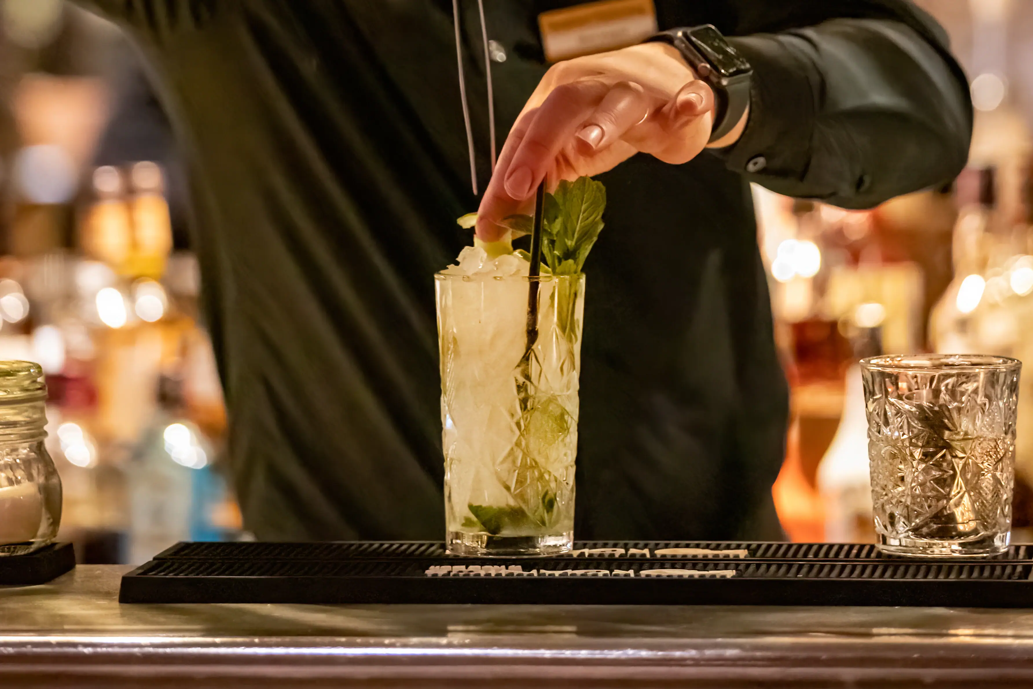 A man holds a pair of tongs to a drink.