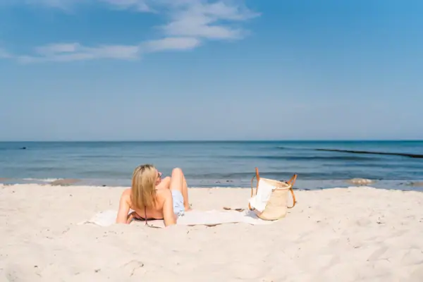 A woman lies on a towel on the beach.