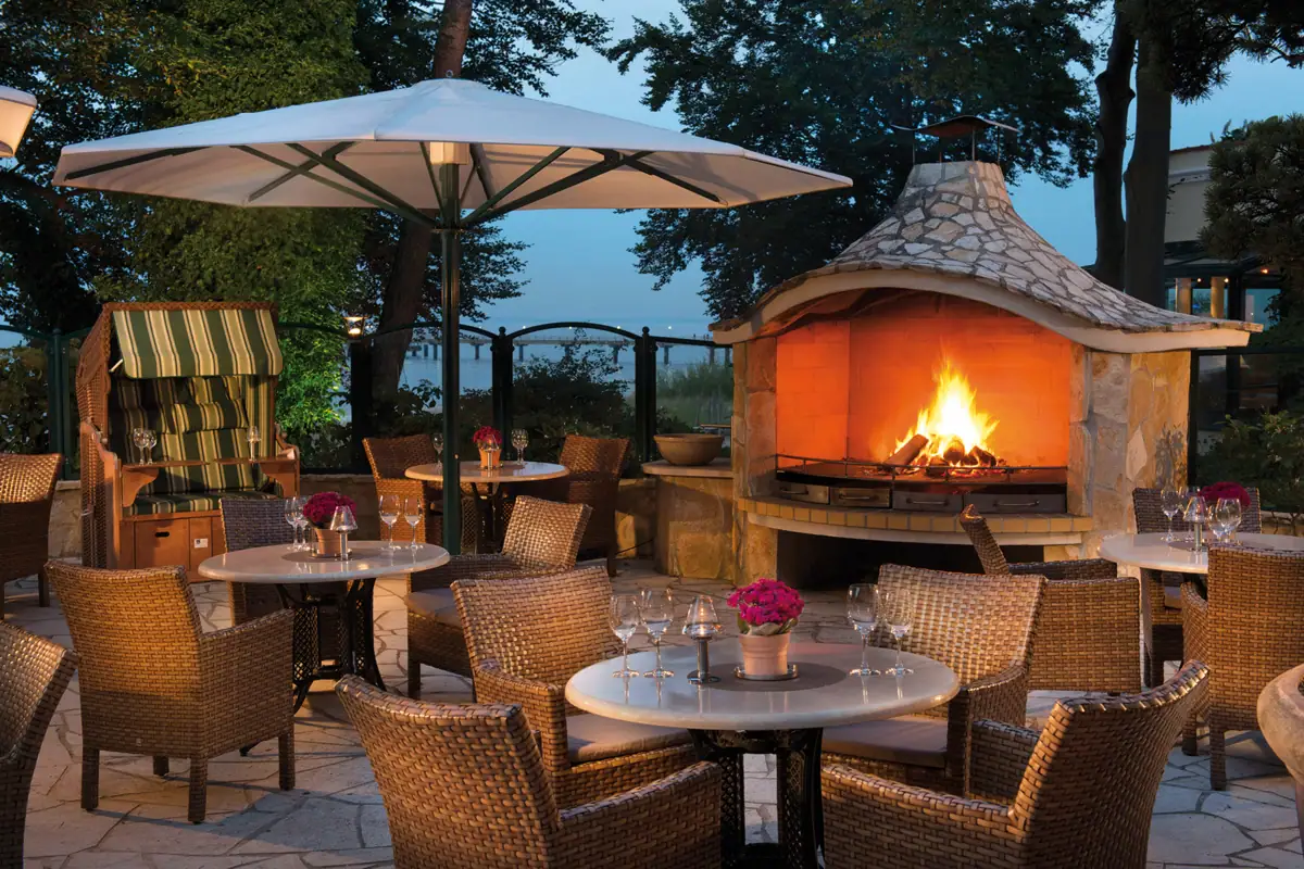 A table and chairs around an outdoor fireplace.