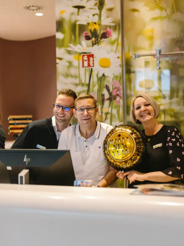 A group of people stand at the reception and smile into the camera.