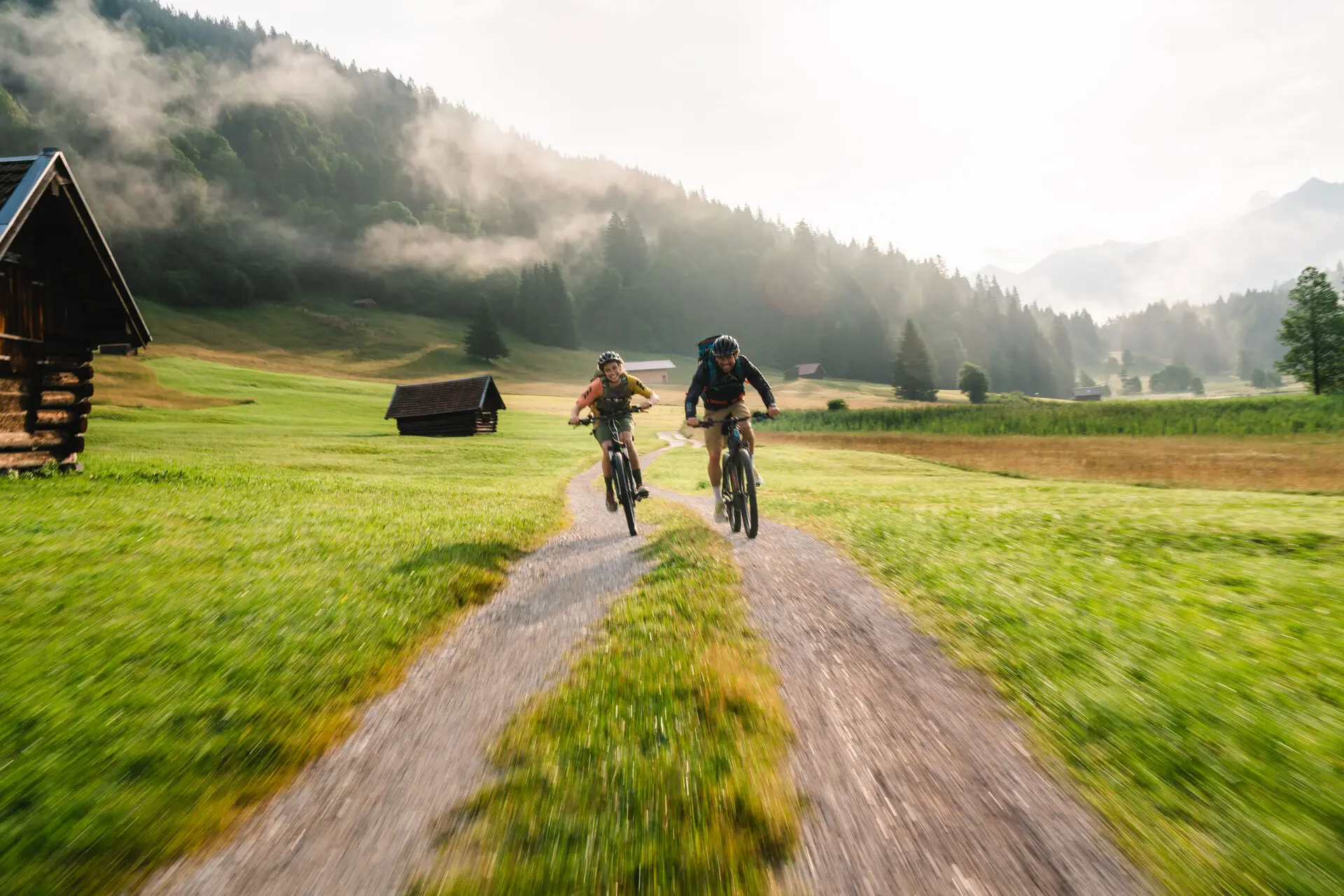 Two people riding bicycles on a dirt road