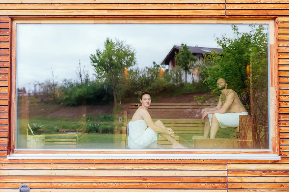 A man and a woman are sitting on a bench in a sauna.