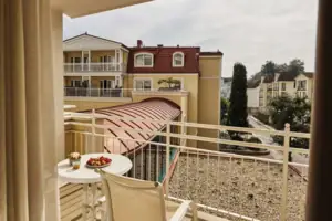 Balcony with table and chairs with a plate of food on it.