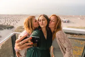 Eine Gruppe von Frauen stehen auf einem Balkon mit Meerblick und macht ein Selfie.