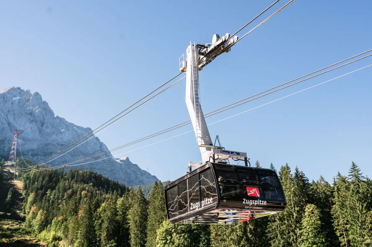 The Zugspitz cable car with trees and mountains in the background.