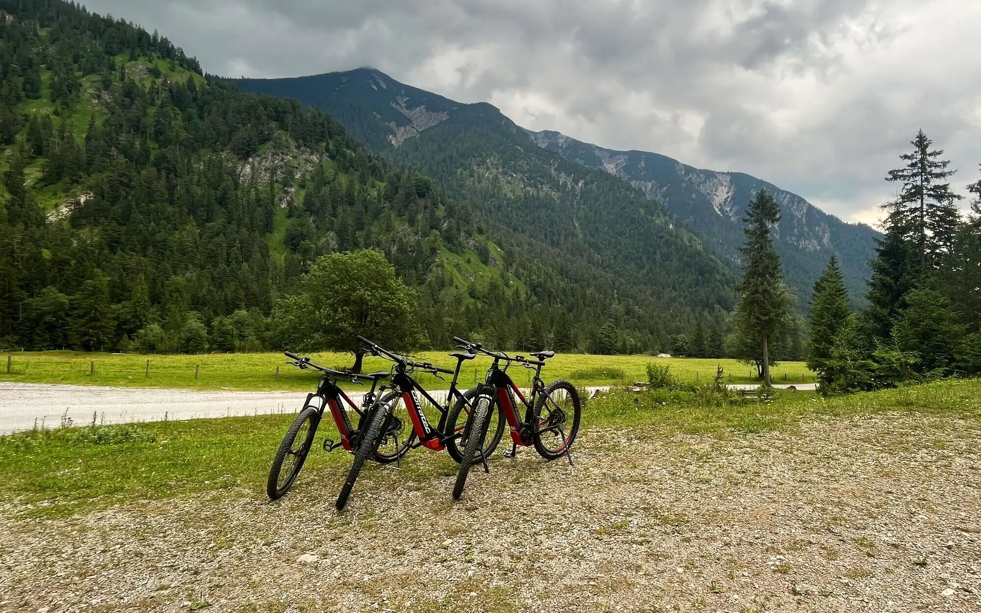 Group of bicycles on a gravel road with mountains in the background.