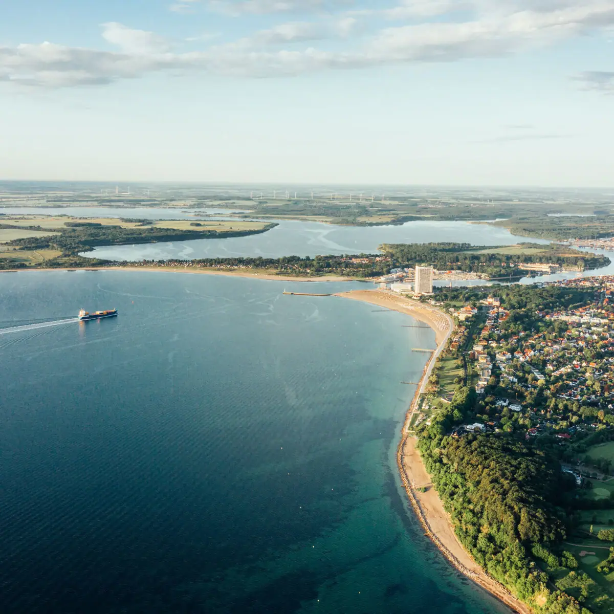Aerial view of the Baltic Sea region of Travemünde and a coastal town under a cloudy sky.