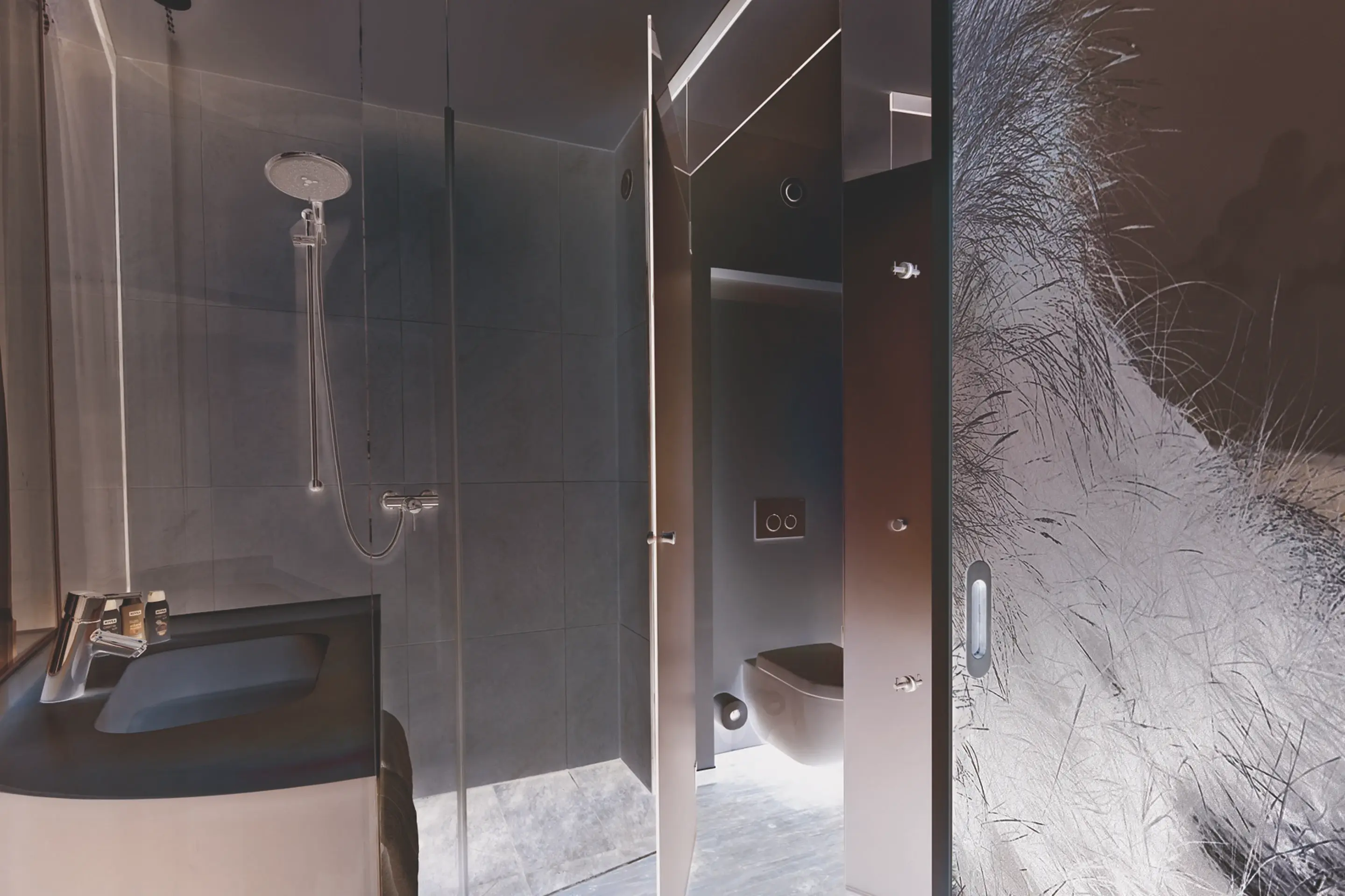 Modern bathroom with a glass-enclosed shower, a sleek sink design, and a separate area for the toilet, featuring contemporary finishes and subtle lighting for a sophisticated look.