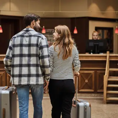 A man and a woman with luggage in a hotel lobby.