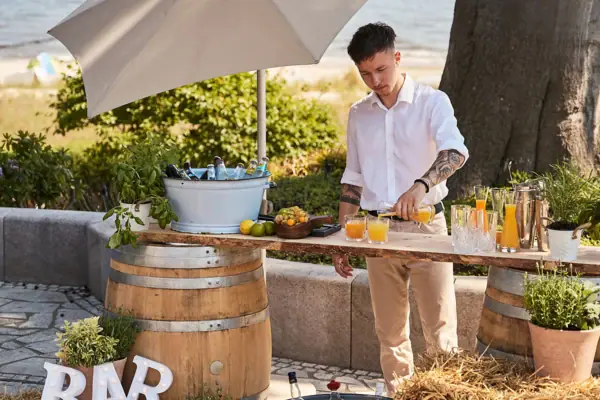 A man is standing by a table with drinks on it.