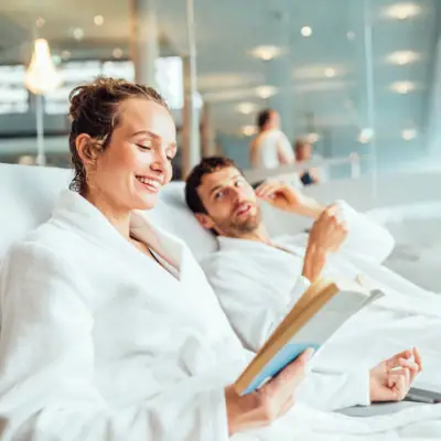 Day SPA at aja A man and a woman in bathrobes are reading a book.