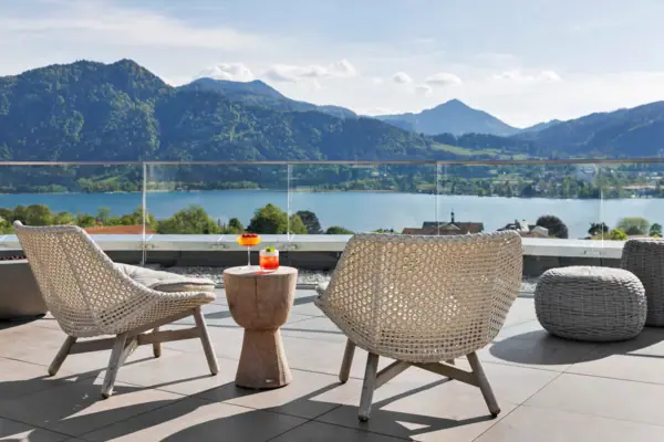 A table and chairs on a terrace overlooking a lake.