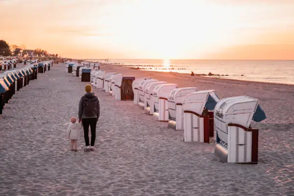 A woman and a child are walking along the beach.