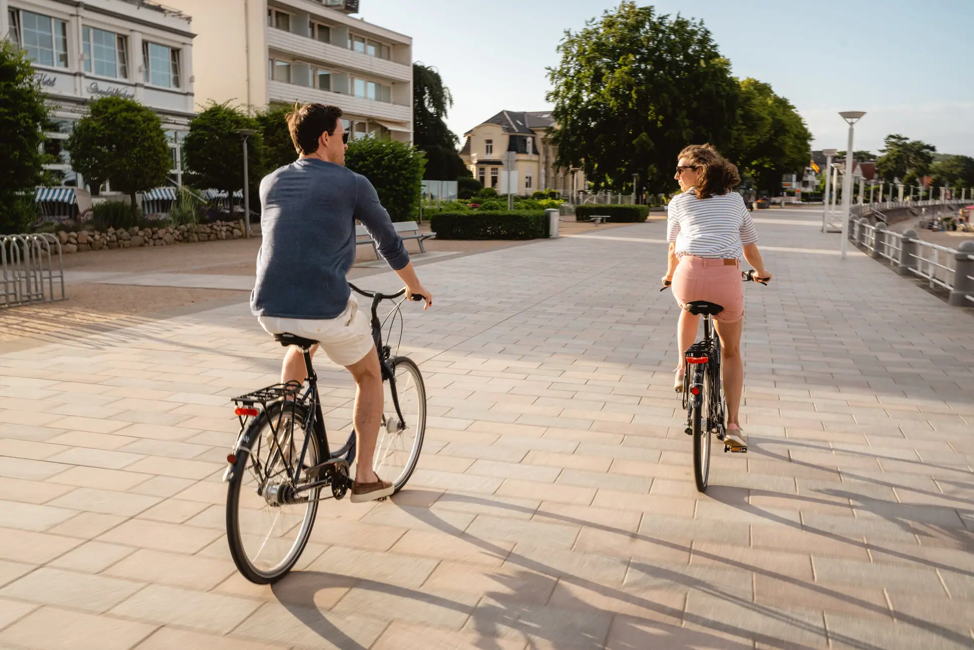 A man and a woman ride bicycles on a paved path.