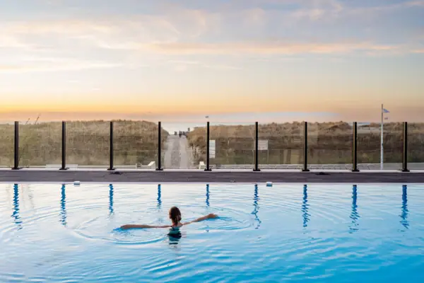 A woman is swimming in the outdoor pool at the aja Warnemünde.