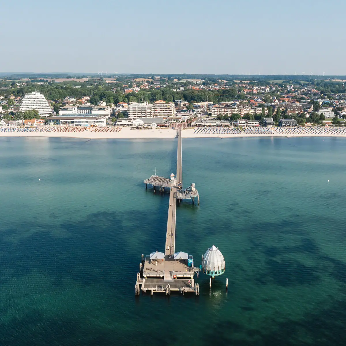 Long jetty on a body of water with a clear sky in the background.