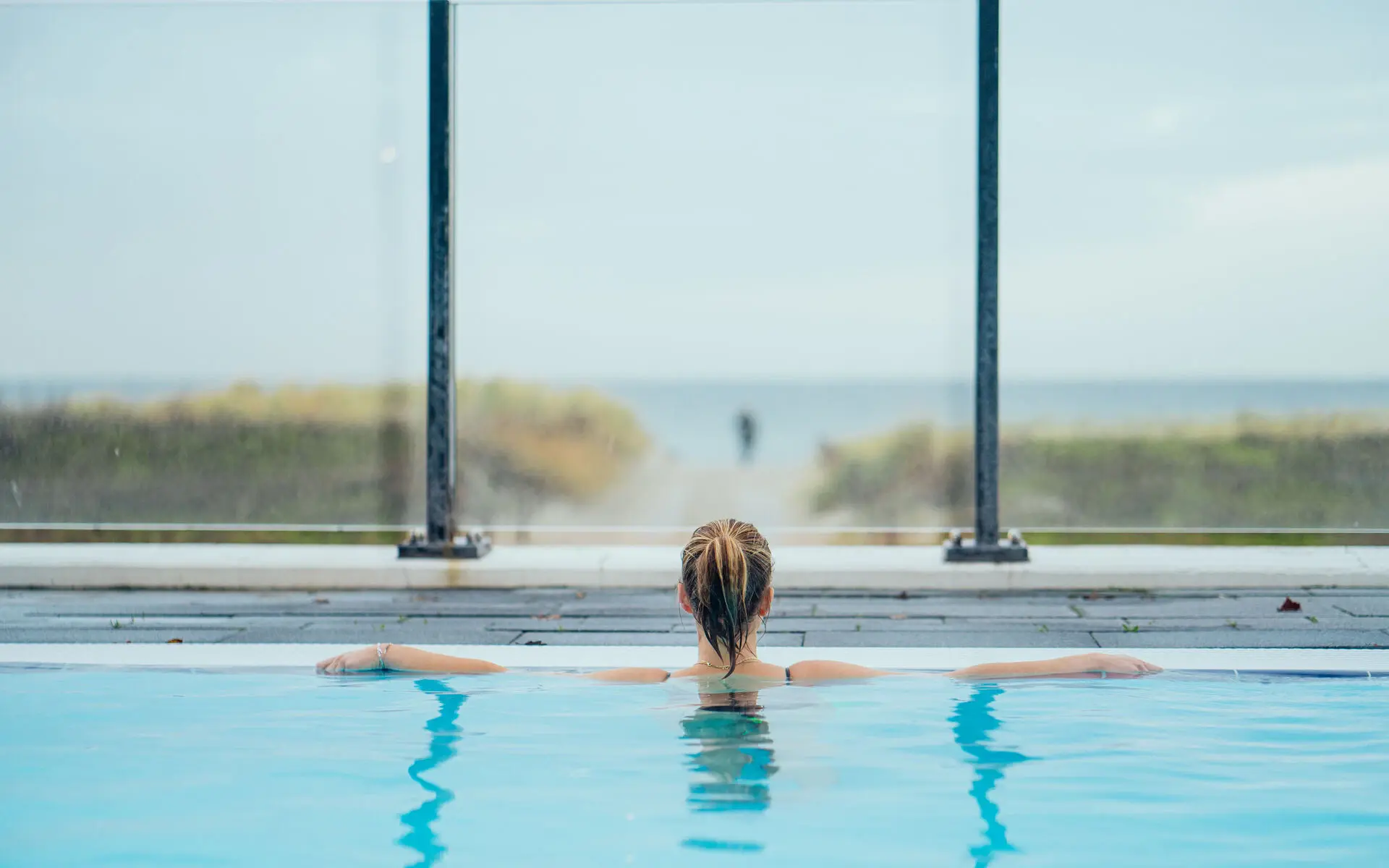 A woman relaxes at the edge of an outdoor pool