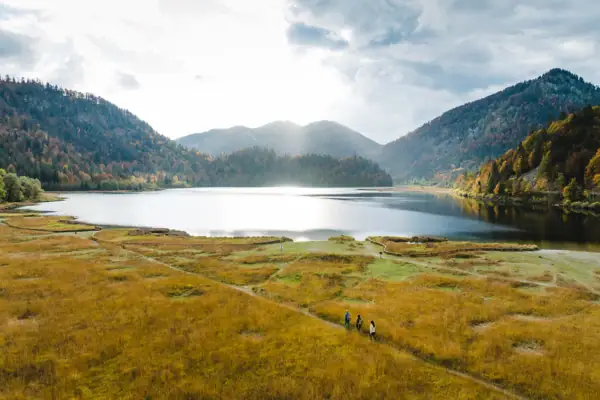 A group of people walk along a path by the lake.