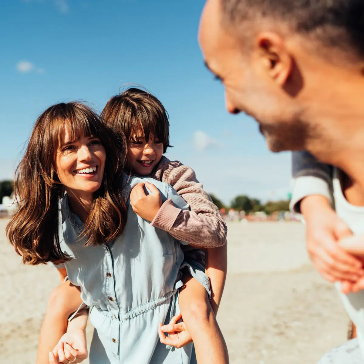 A man and a woman hold a child on the beach.