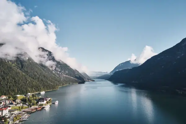 A body of water with a house and mountains in the background.