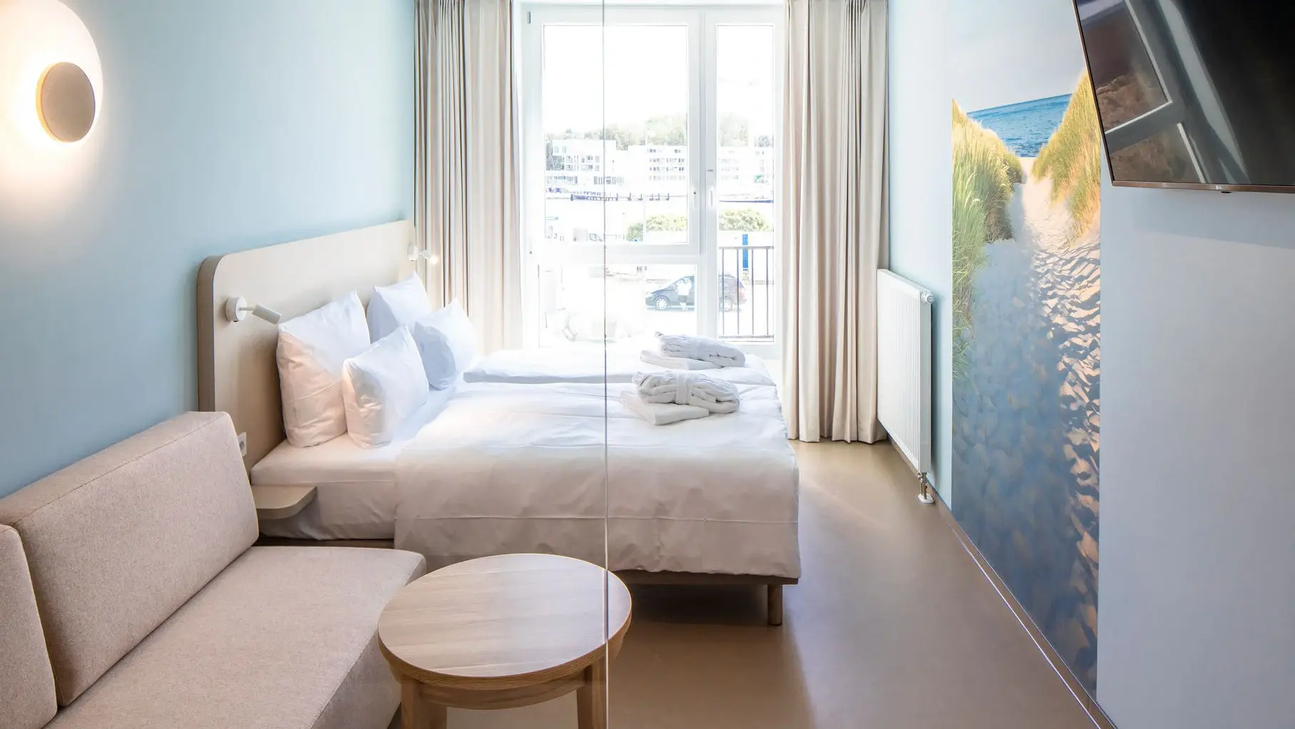 A room with light blue walls containing a bed and a small sofa