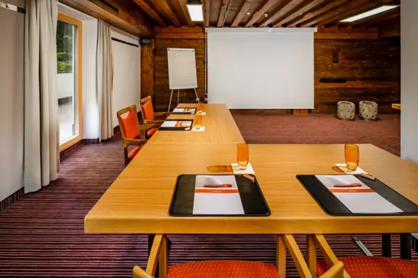 A room with a large white screen and several tables.