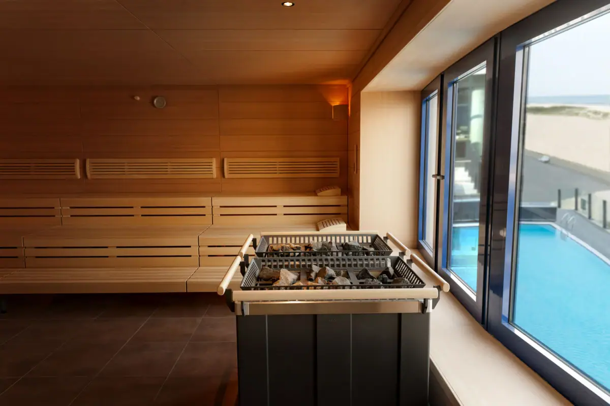 A sauna with a window through which you can see a swimming pool.
