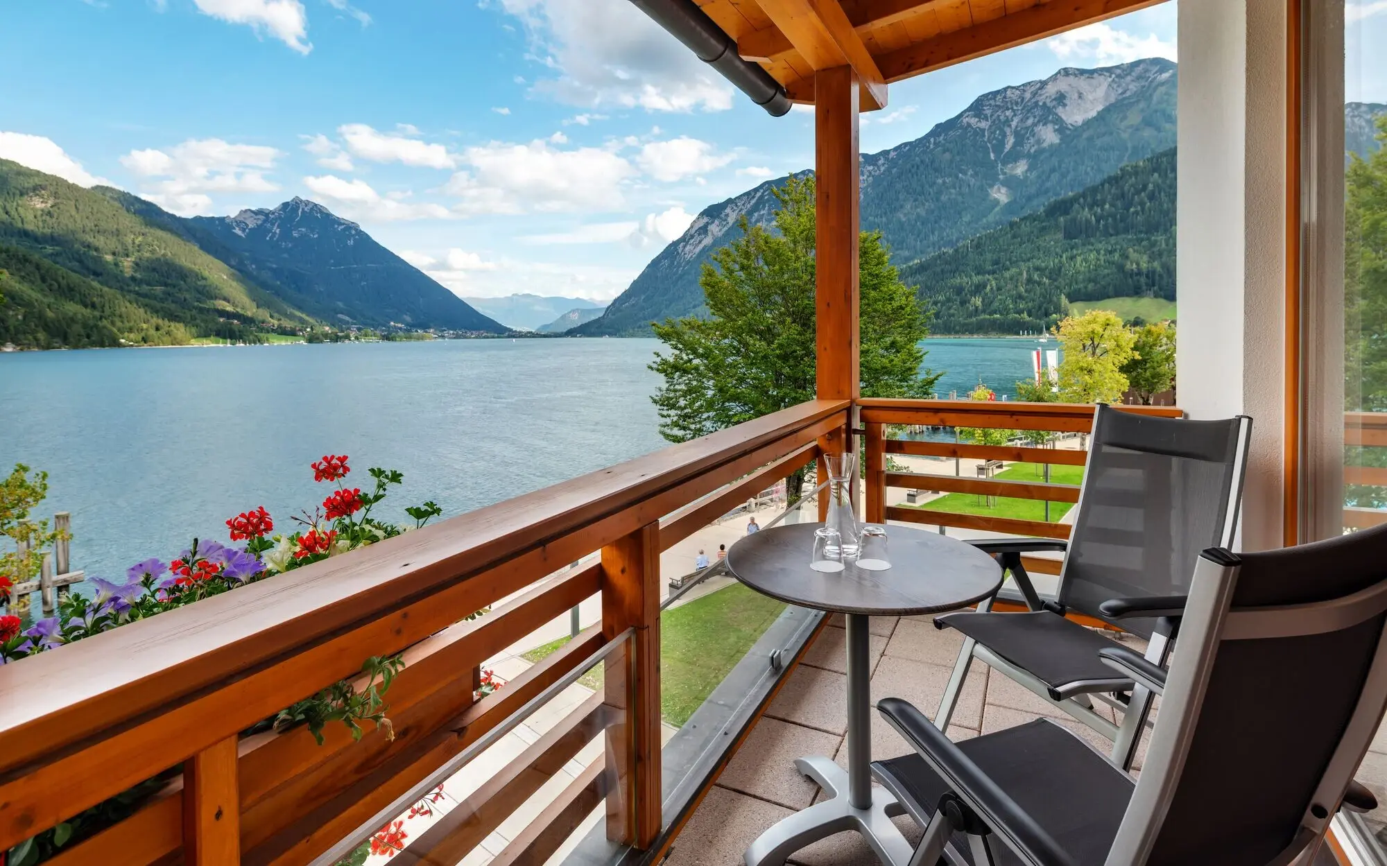 Balcony with table and chairs with a view of the Achensee and mountains.