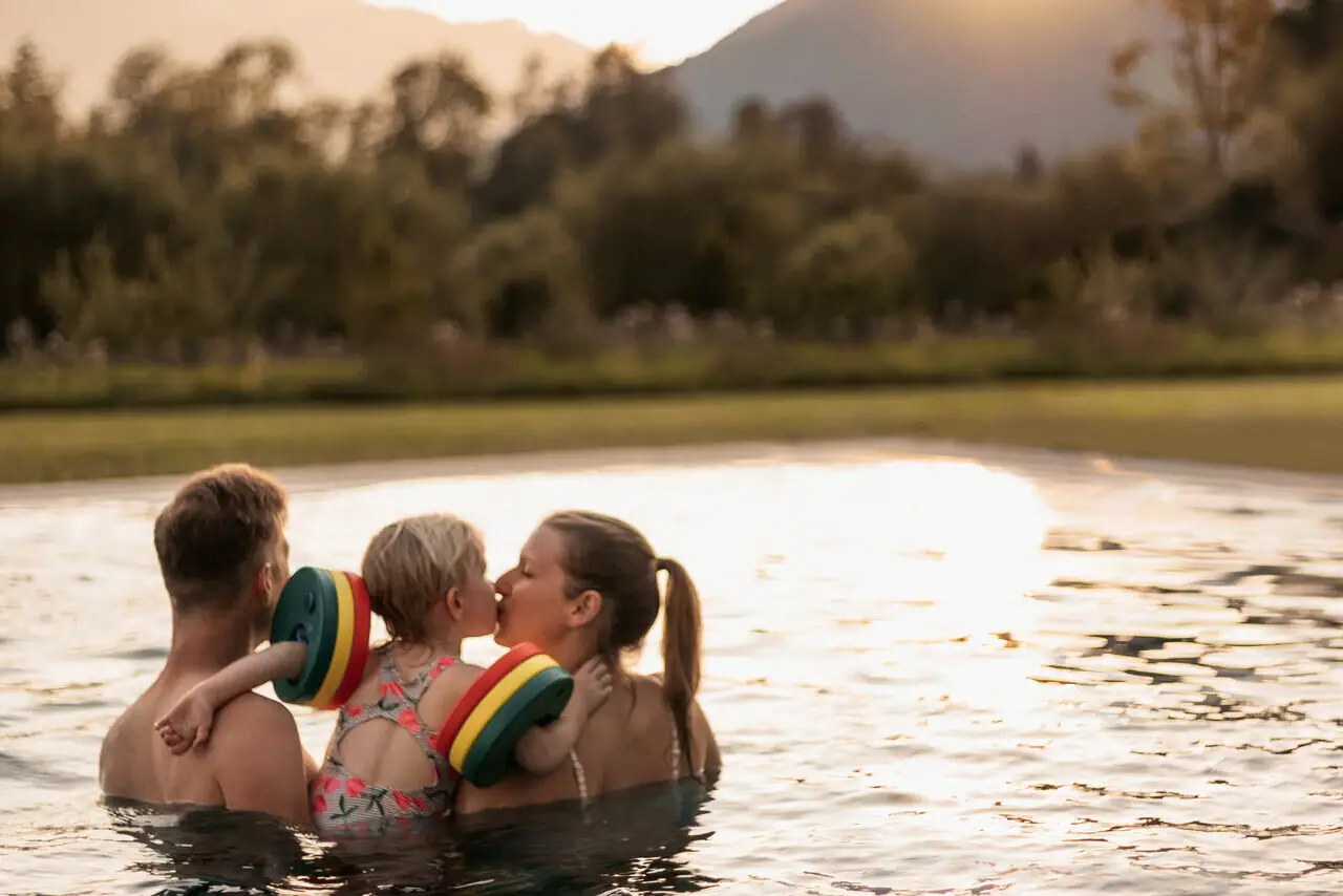 A group of people in the pool, a child gives a kiss.