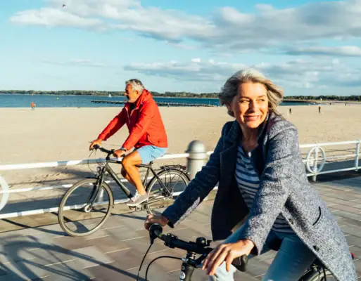 Cycling A man and a woman ride along the beach on bicycles.