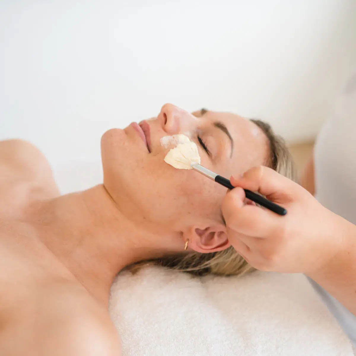Woman lying with a brush on her face.