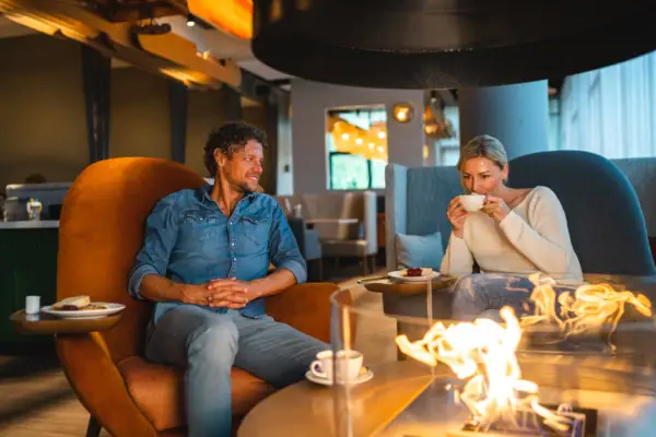 Kaffeepause Ein Mann und eine Frau sitzen auf Stühlen und trinken Kaffee.