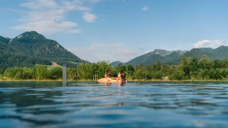 A couple in the pool with mountains in the background.