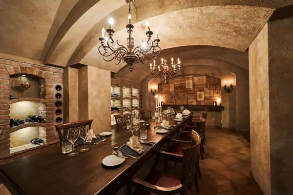 A long table with plates and glasses and a chandelier.