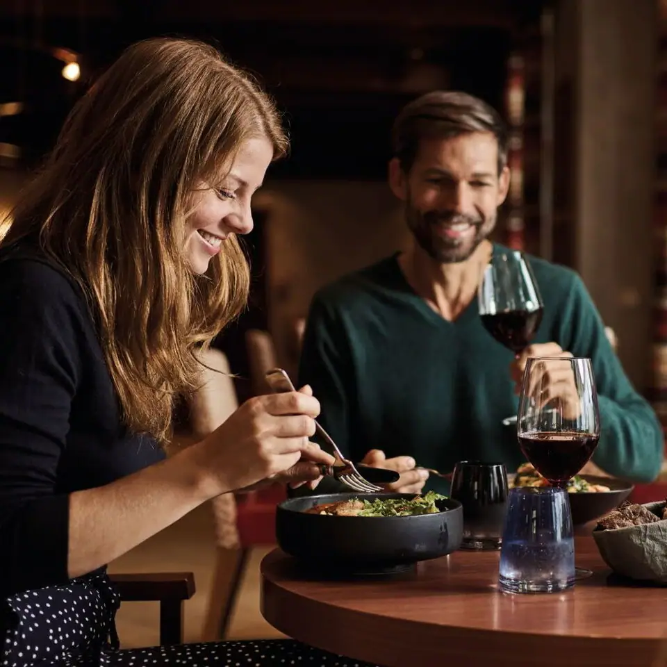 A man and a woman are eating at a table.