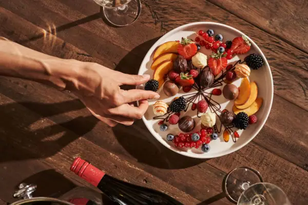 Dessert A hand reaches for a plate of fruit.