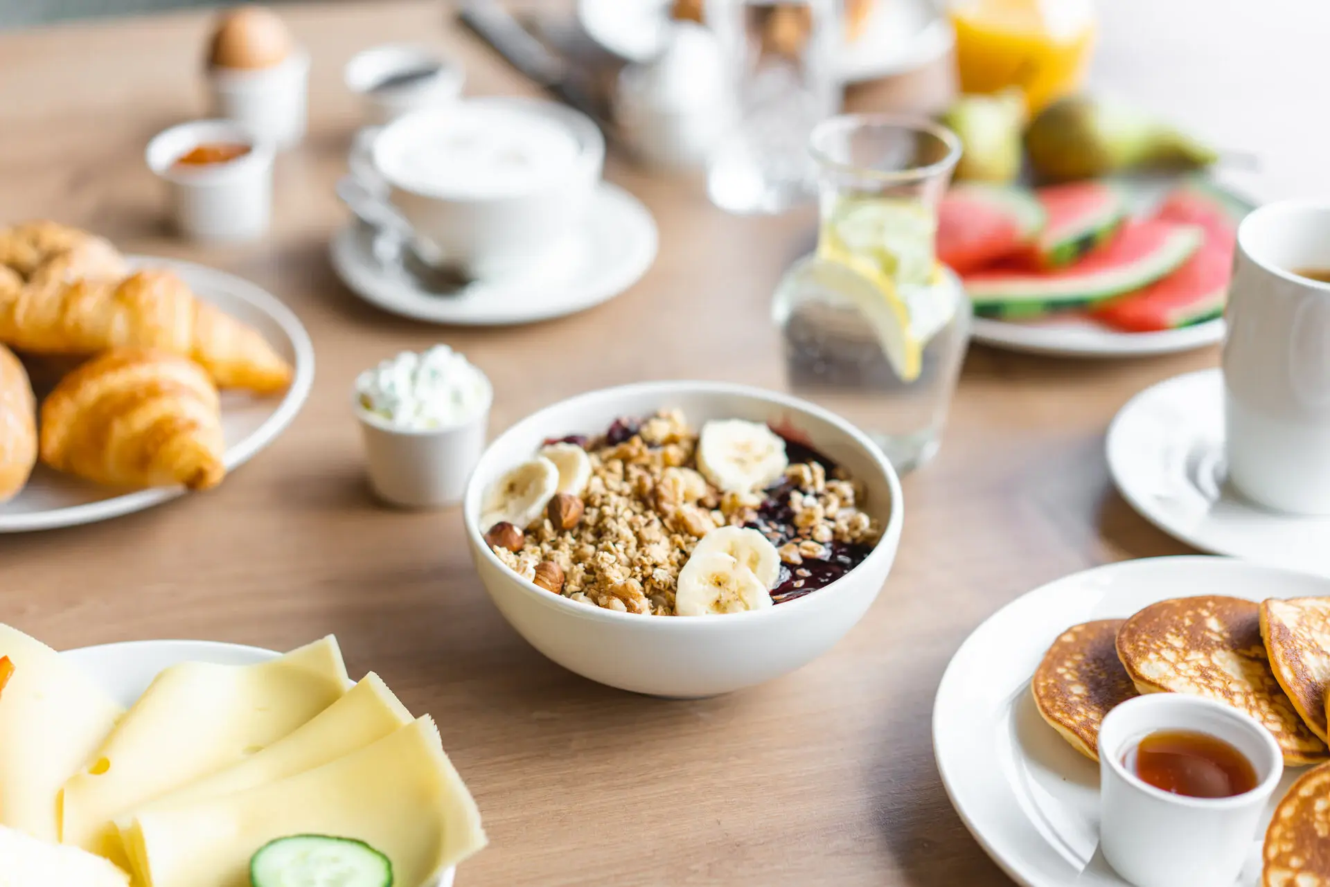 Bowl with muesli, bananas and pancakes on a wooden table