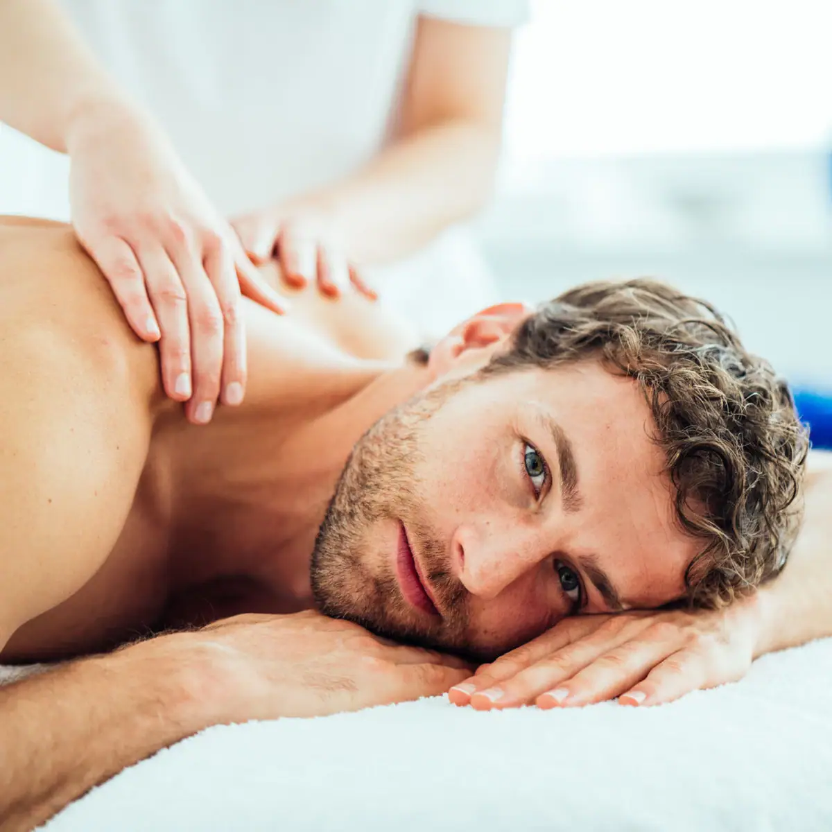 Relaxation with aja A man lies on a massage table and has his neck massaged.