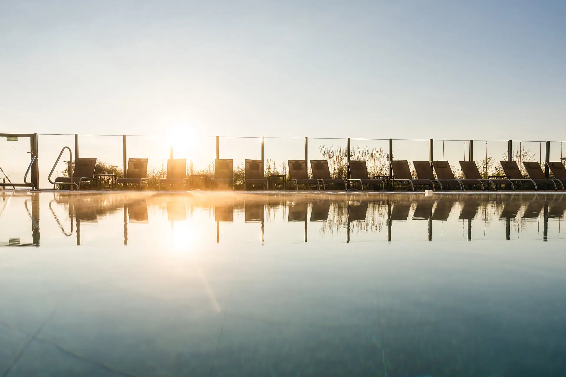 A pool with chairs and an outdoor fence.