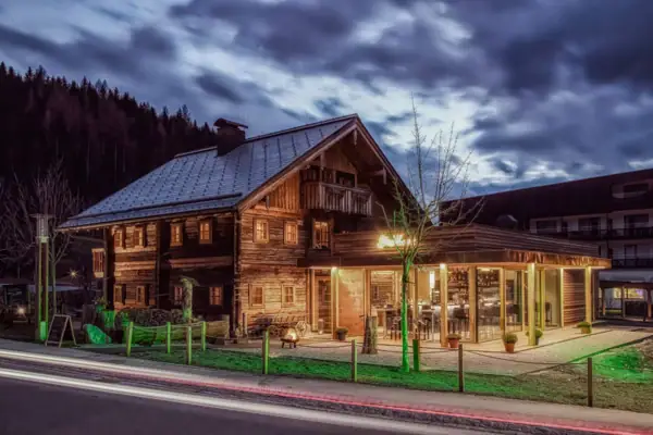 A rustic wooden house with warm lighting at dusk. 