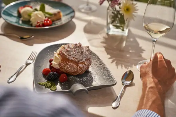 A plate of dessert and berries next to a glass of wine.