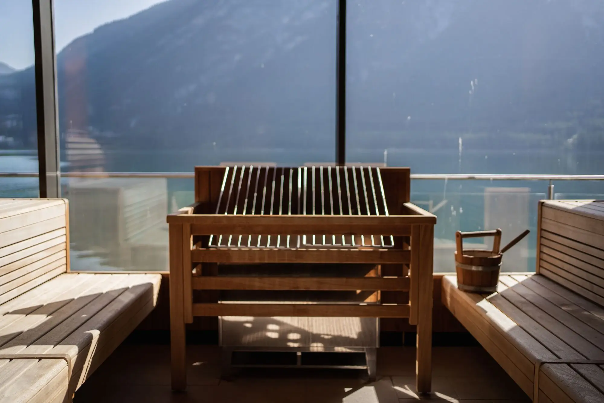 Panoramic sauna with a view of a lake and a mountain panorama.