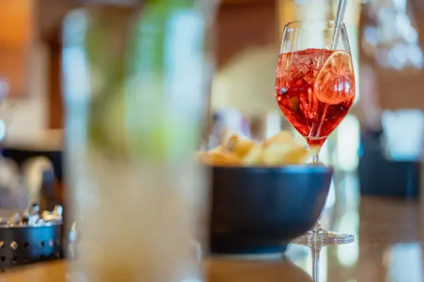 Cocktail A glass of red liquid with a straw next to a bowl of crisps.
