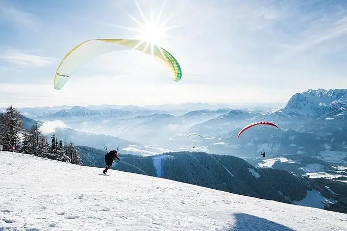 Group of people paragliding on a snowy mountain.